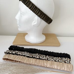 May include: Three satin headbands in different patterns: black, leopard print, and beige. The headbands are gathered and have a stretchy fit.