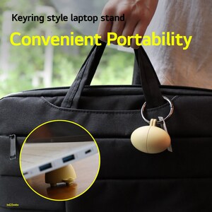 May include: A yellow laptop stand in the shape of an egg is attached to a black laptop bag with a silver keyring. The text "Keyring style laptop stand Convenient Portability" is displayed above the image.