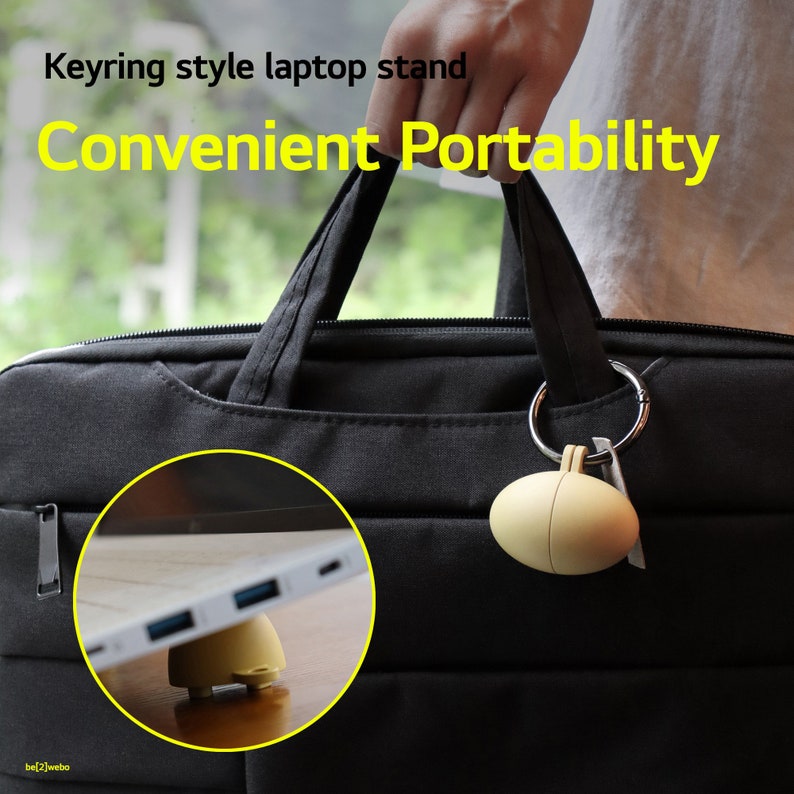 May include: A yellow laptop stand in the shape of an egg is attached to a black laptop bag with a silver keyring. The text "Keyring style laptop stand Convenient Portability" is displayed above the image.