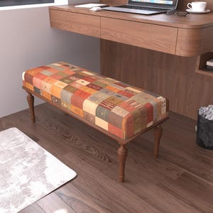 May include: A rectangular bench featuring a cushioned seat upholstered in a patchwork fabric with various geometric patterns in shades of orange, red, brown, and cream, supported by four turned wooden legs with a dark brown finish.
