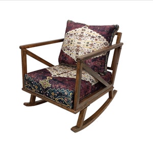 May include: A wooden rocking chair with a patterned cushion and backrest. The cushion and backrest feature a design with burgundy, cream, and navy blue colors. The chair has a dark brown wooden frame.