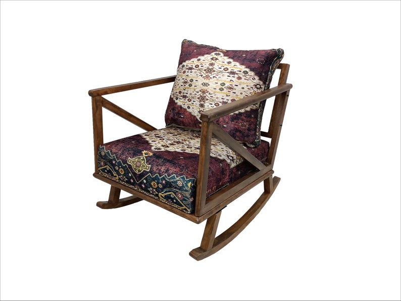 May include: A wooden rocking chair with a patterned cushion and backrest. The cushion and backrest feature a design with burgundy, cream, and navy blue colors. The chair has a dark brown wooden frame.