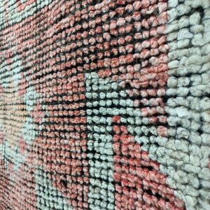 以下が含まれることがあります： ピンク、白、黒の幾何学模様が織り込まれた敷物のクローズアップ。