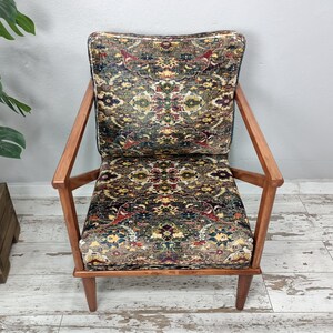 May include: A brown wooden armchair with a patterned fabric seat and back. The fabric features a colorful design with shades of red, blue, green, and yellow.