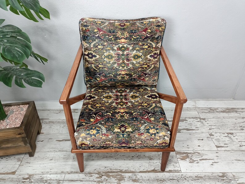 May include: A brown wooden armchair with a patterned fabric seat and back. The fabric features a colorful design with shades of red, blue, green, and yellow.
