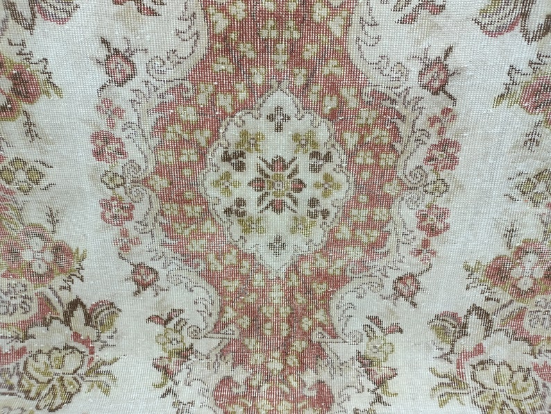 Op de afbeelding: Een vintage tapijt met een bloemenpatroon in tinten bruin, rood en wit. Het tapijt heeft een centraal medaillon met een herhalend patroon van bloemen en bladeren.