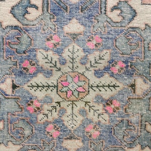 Pode incluir: Close-up de um tapete vintage com um padr&atilde;o floral azul e branco. O tapete tem um medalh&atilde;o central com um design rosa e verde. O tapete &eacute; tecido com grande detalhe.