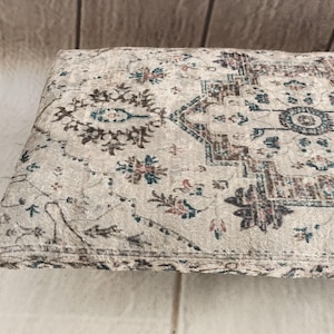 a close-up view of a decorative rug or cushion with a floral pattern on a wooden surface.