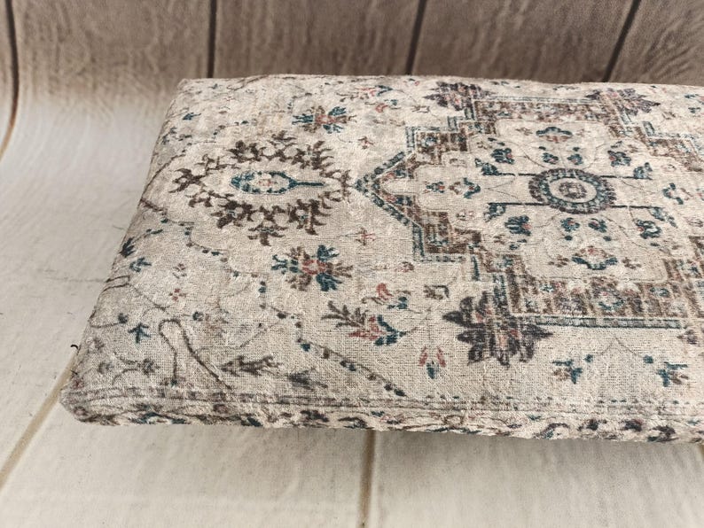 a close-up view of a decorative rug or cushion with a floral pattern on a wooden surface.