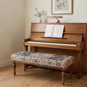 a wooden piano with a bench in front of it, and a framed picture on the wall above the piano.