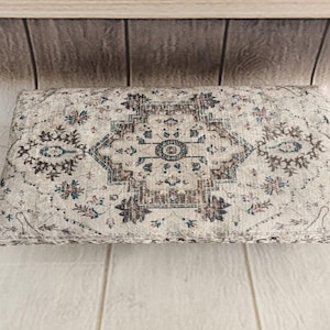 a decorative rug or cushion with a floral pattern, placed on a wooden surface.
