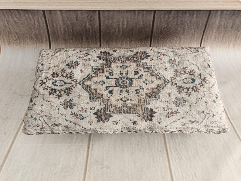 a decorative rug or cushion with a floral pattern, placed on a wooden surface.