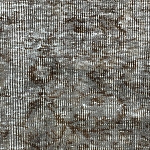 May include: Close-up of a textured fabric with a white and brown pattern. The fabric has a woven appearance and a slightly distressed look.