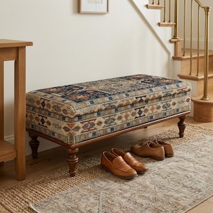 a wooden bench with a colorful, patterned cushion placed on a rug in a hallway. There are a pair of brown shoes and a pair of brown loafers placed on the rug next to the bench.