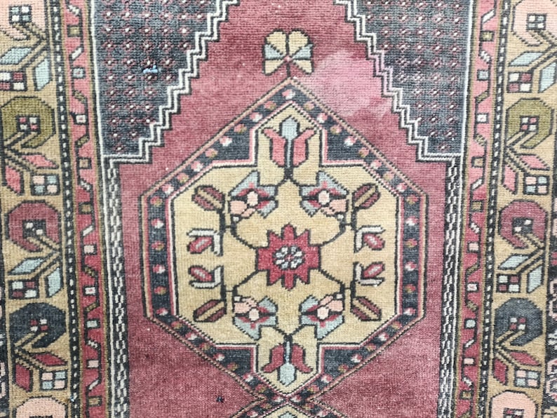 May include: A vintage rug with a traditional Persian design. The rug features a central medallion with floral motifs in shades of beige, red, and blue. The border is a repeating pattern of geometric shapes in black, white, and red.
