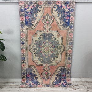 Pode incluir: Um tapete vintage rosa e azul com um padr&atilde;o floral. O tapete tem um aspeto desbotado e desgastado, perfeito para adicionar um toque de estilo bo&eacute;mio &agrave; sua casa.