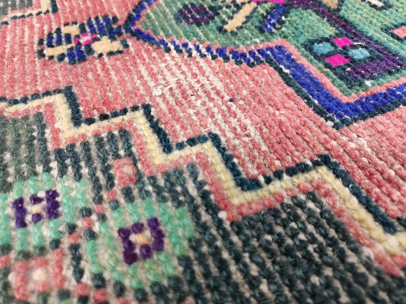 Peut inclure: Gros plan sur un tapis tiss&eacute; color&eacute; avec un motif g&eacute;om&eacute;trique. Le tapis est en laine et a une surface douce et textur&eacute;e.