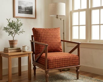 Puede incluir: Un sillón con estructura de madera y un cojín de tela con estampado de pata de gallo en color óxido. La silla cuenta con un respaldo cuadrado, un cojín de asiento y patas de madera torneadas. Está junto a una mesa auxiliar con libros y una planta.