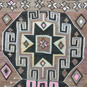 May include: A traditional rug with a geometric pattern in shades of brown, black, white, and pink. The rug features a large central star design surrounded by intricate borders.
