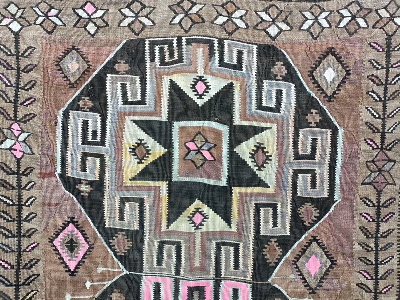 May include: A traditional rug with a geometric pattern in shades of brown, black, white, and pink. The rug features a large central star design surrounded by intricate borders.