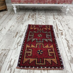 May include: A red, orange, and blue patterned runner rug with a fringe border. The rug has a geometric design with a central motif.