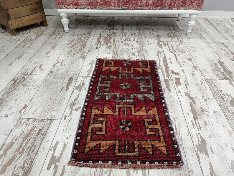 May include: A red, orange, and blue patterned runner rug with a fringe border. The rug has a geometric design with a central motif.