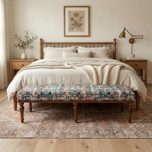 May include: A bedroom interior with a wooden bed, bedside tables, and a patterned bench. The bed is dressed in neutral-toned bedding and a cream throw. A framed botanical print is mounted above the bed, creating a serene atmosphere.