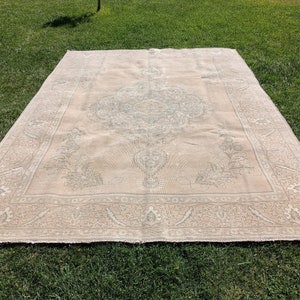 May include: A large, off-white rug with a delicate floral pattern in a lighter shade of gray. The rug has a central medallion with a repeating pattern of leaves and flowers.