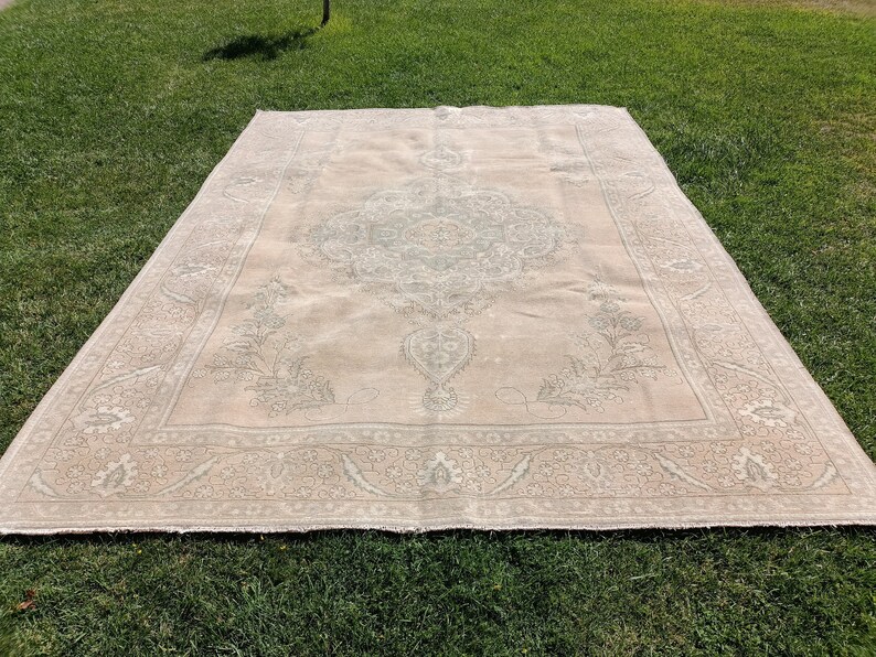 May include: A large, off-white rug with a delicate floral pattern in a lighter shade of gray. The rug has a central medallion with a repeating pattern of leaves and flowers.