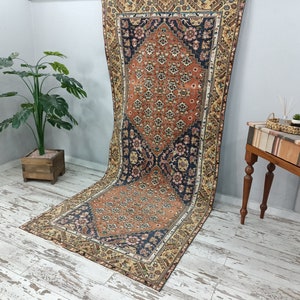 May include: A vintage Persian rug with a floral pattern in shades of orange, blue, and cream. The rug has a distressed look and is perfect for adding a touch of traditional style to any room.