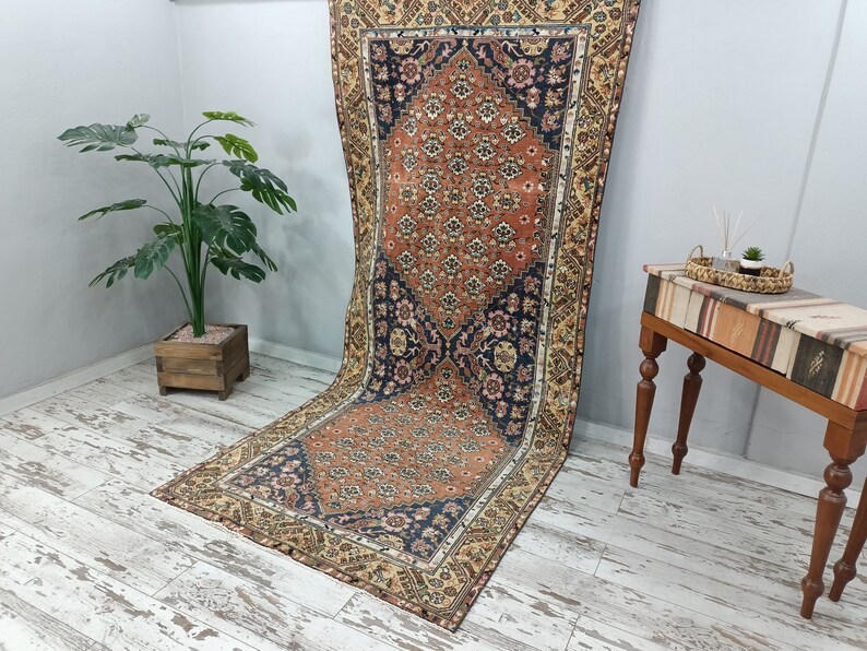 May include: A vintage Persian rug with a floral pattern in shades of orange, blue, and cream. The rug has a distressed look and is perfect for adding a touch of traditional style to any room.