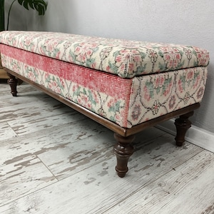 May include: A long, rectangular storage bench with a floral patterned fabric top and wooden legs. The fabric is a mix of cream, pink, and green.