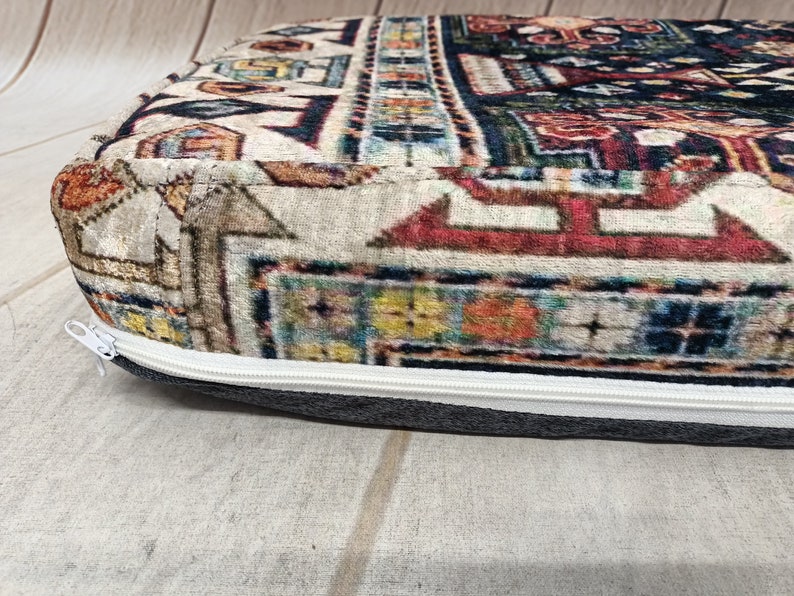 Pu&ograve; includere: Primo piano di un cuscino con cerniera e tessuto a fantasia colorata. Il tessuto presenta un design geometrico con sfumature di rosso, blu, giallo e bianco.