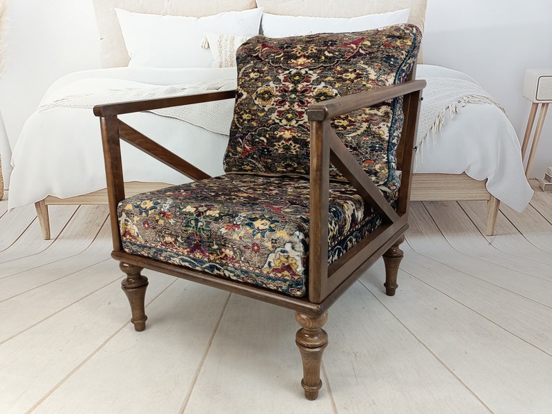 May include: A dark brown wooden armchair with a patterned fabric seat and back. The chair has a unique X-shaped design on the back and legs.