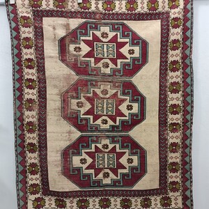 May include: A vintage rug with a cream background and three red, blue, and green octagonal medallions with star-shaped designs. The rug has a border with a repeating pattern of green, red, and blue.