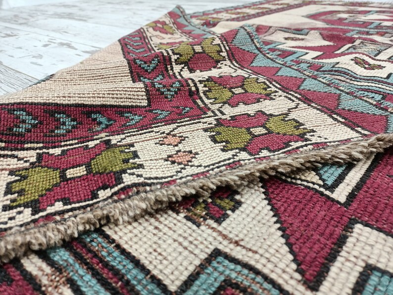 May include: Close-up of a beige, red, green, and blue patterned rug with a fringe border.