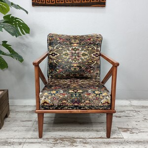 May include: A wooden armchair with a patterned fabric upholstery. The chair has a dark wood frame and a geometric pattern on the fabric.