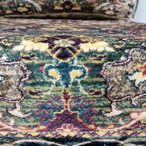 May include: Close-up of a chair with a patterned fabric upholstery. The fabric features a colorful design with shades of green, blue, red, and beige.