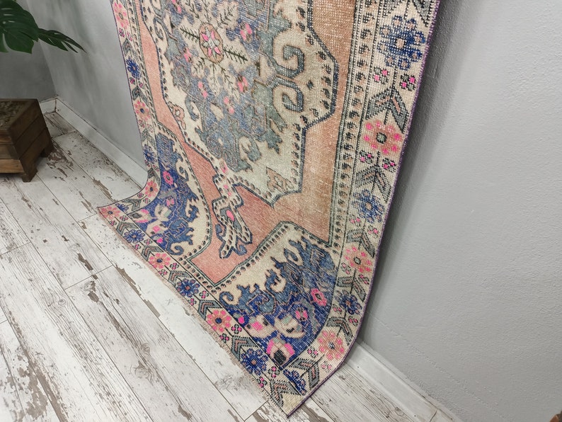 Pode incluir: Um tapete vintage com um padr&atilde;o floral desbotado em rosa, azul e branco. O tapete tem um visual desgastado e &eacute; perfeito para adicionar um toque de estilo bo&ecirc;mio a qualquer c&ocirc;modo.