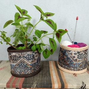May include: Two fabric baskets with a patterned design. One basket holds a green plant and the other holds yarn and knitting needles.