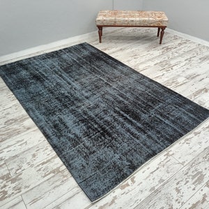 May include: A blue and black distressed rug with a faded, vintage look. The rug has a rectangular shape and is laid out on a whitewashed wood floor.