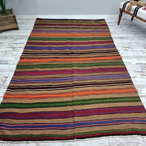 May include: A striped rug with brown, orange, green, purple, and blue stripes. The rug is made of wool and has a traditional design.