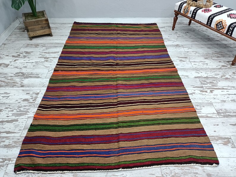 May include: A striped rug with brown, orange, green, purple, and blue stripes. The rug is made of wool and has a traditional design.