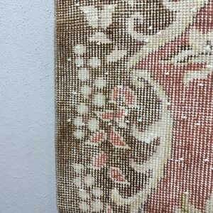 Op de afbeelding: Close-up van een bruin, rood en wit gepatroneerd tapijt met een gedetailleerd bloemenontwerp. Het tapijt heeft een geweven textuur en is gemaakt van een zacht materiaal.