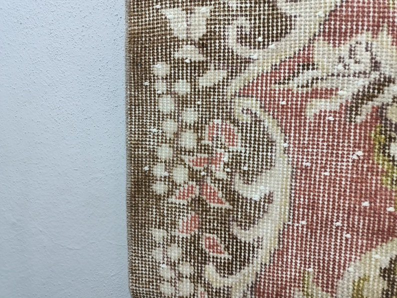Op de afbeelding: Close-up van een bruin, rood en wit gepatroneerd tapijt met een gedetailleerd bloemenontwerp. Het tapijt heeft een geweven textuur en is gemaakt van een zacht materiaal.