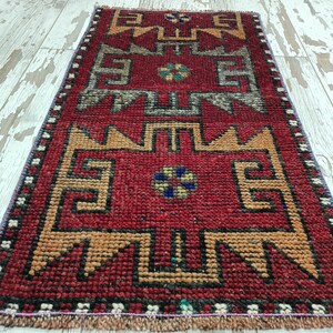 May include: A red, orange, and blue patterned runner rug with a geometric design. The rug has a fringe border.