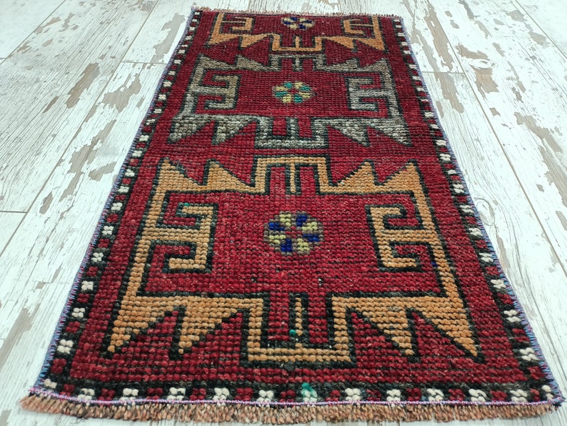 May include: A red, orange, and blue patterned runner rug with a geometric design. The rug has a fringe border.