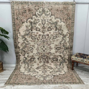 May include: A vintage rug with a floral pattern in shades of beige, brown, and green. The rug has a distressed look and is perfect for adding a touch of bohemian style to any room.