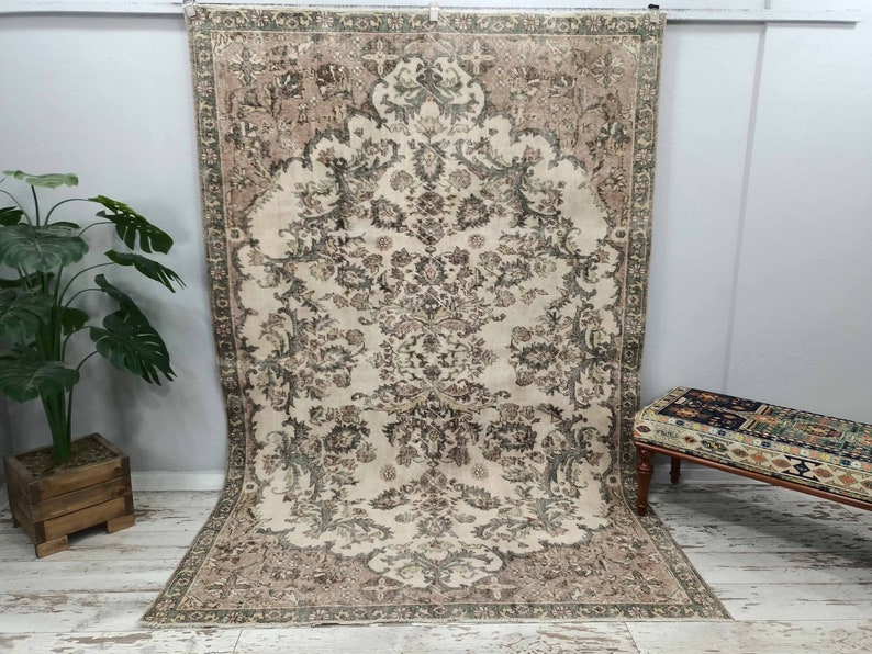 May include: A vintage rug with a floral pattern in shades of beige, brown, and green. The rug has a distressed look and is perfect for adding a touch of bohemian style to any room.