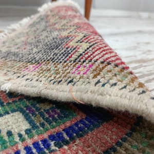 Peut inclure: Gros plan sur un tapis tiss&eacute; multicolore avec une bordure &agrave; franges. Le tapis est pli&eacute;, r&eacute;v&eacute;lant l'envers du tissu.